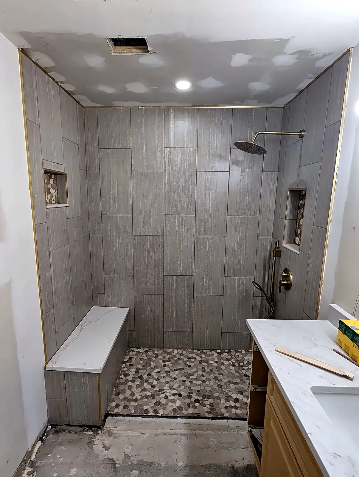 Walk-in tile shower with bench, niche and pebble floor