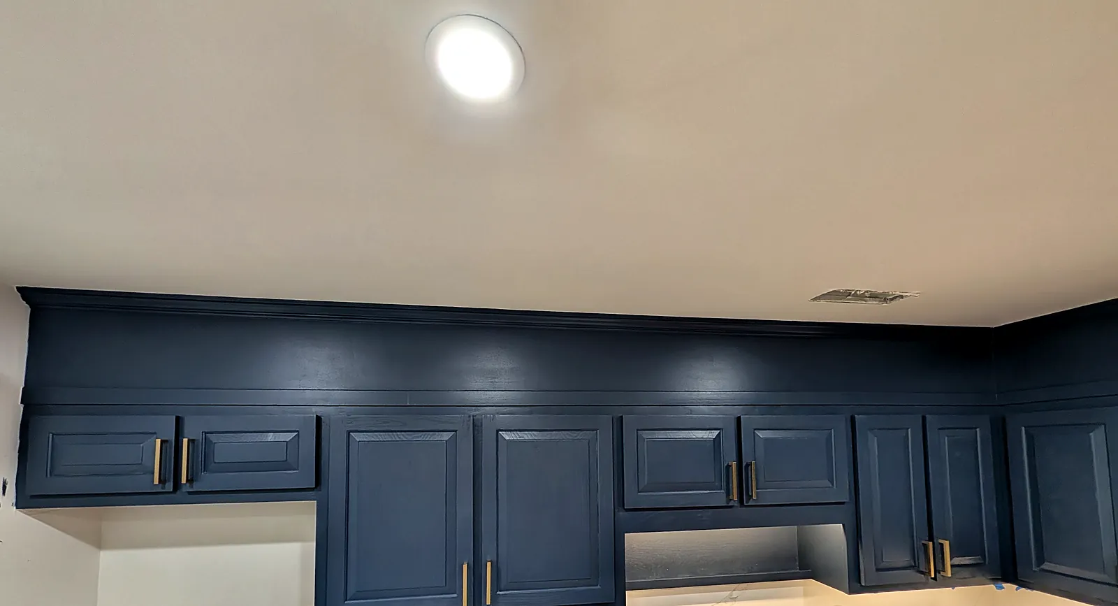 Navy kitchen cabinetry with under-cabinet lighting going in