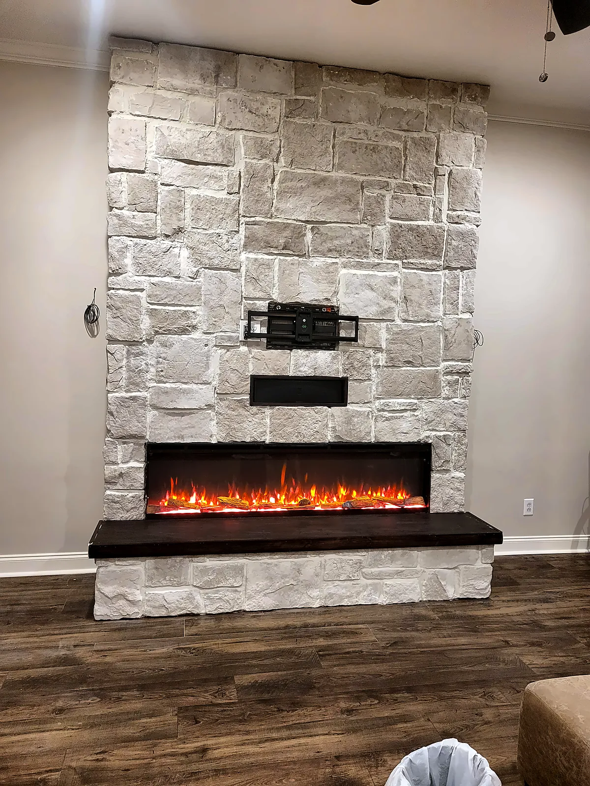 Floor-to-ceiling stacked stone fireplace wall with linear fireplace and floating hearth