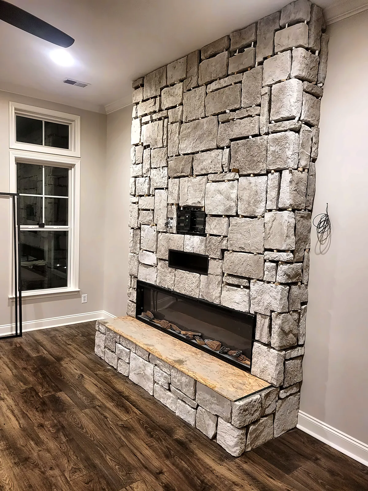 Stacked stone fireplace wall from the side with window