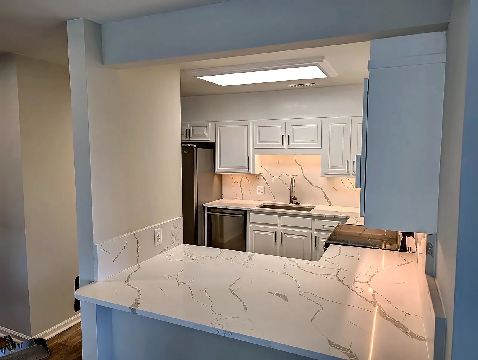 Kitchen peninsula with quartz countertop and white shaker cabinets