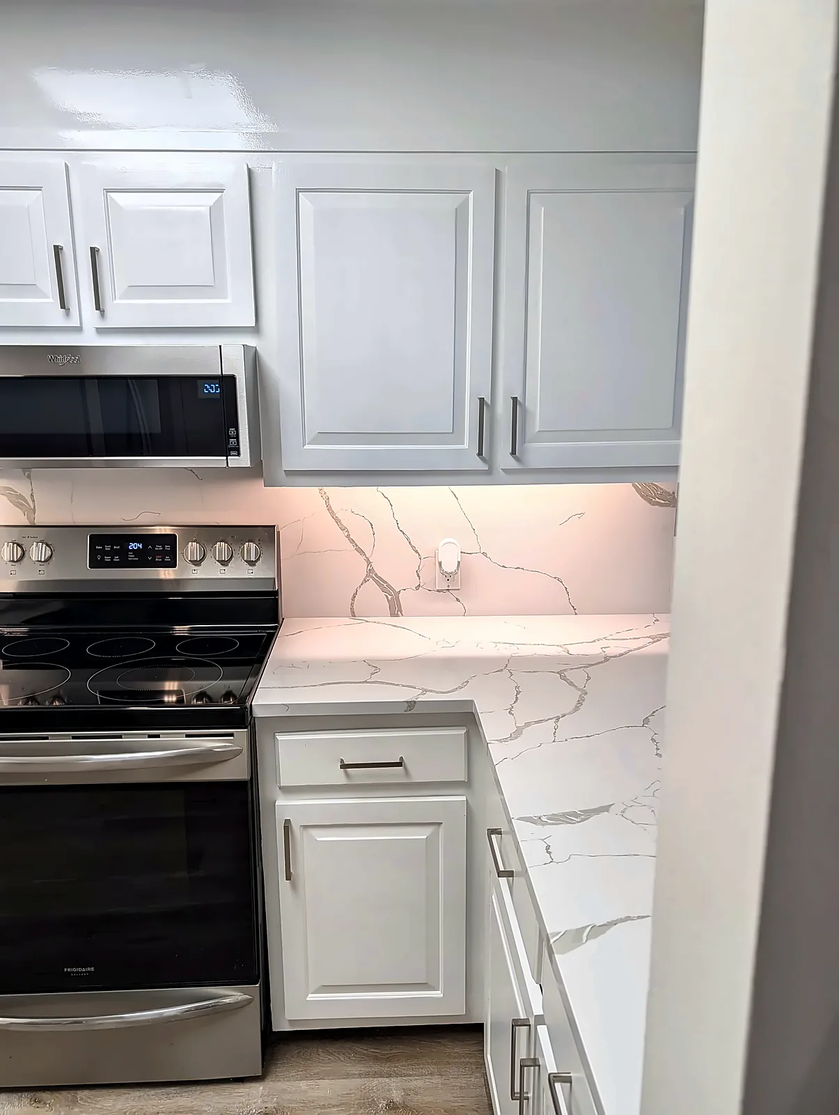 White shaker kitchen with stainless range and microwave