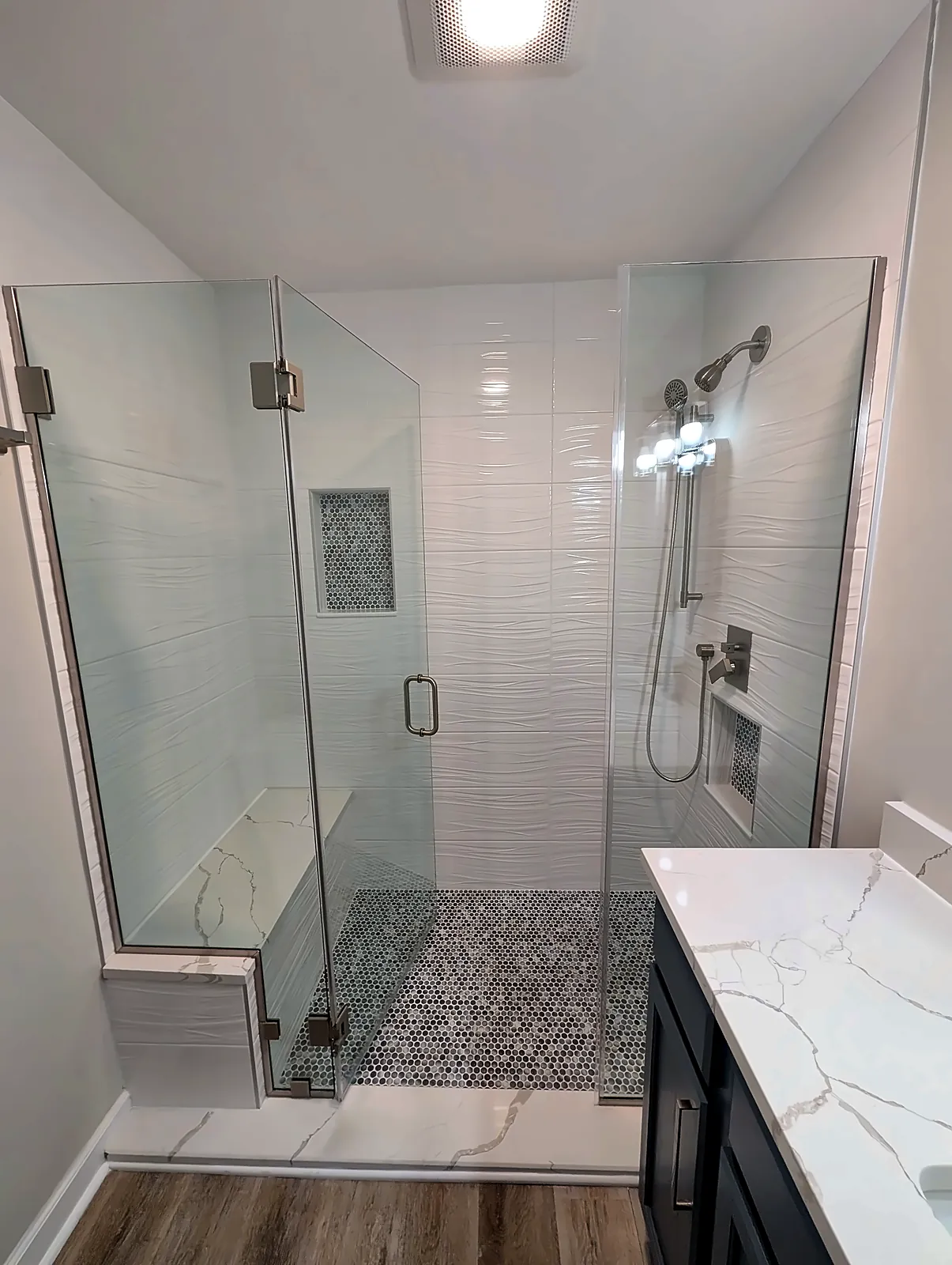 Frameless glass shower with white subway tile and pebble floor