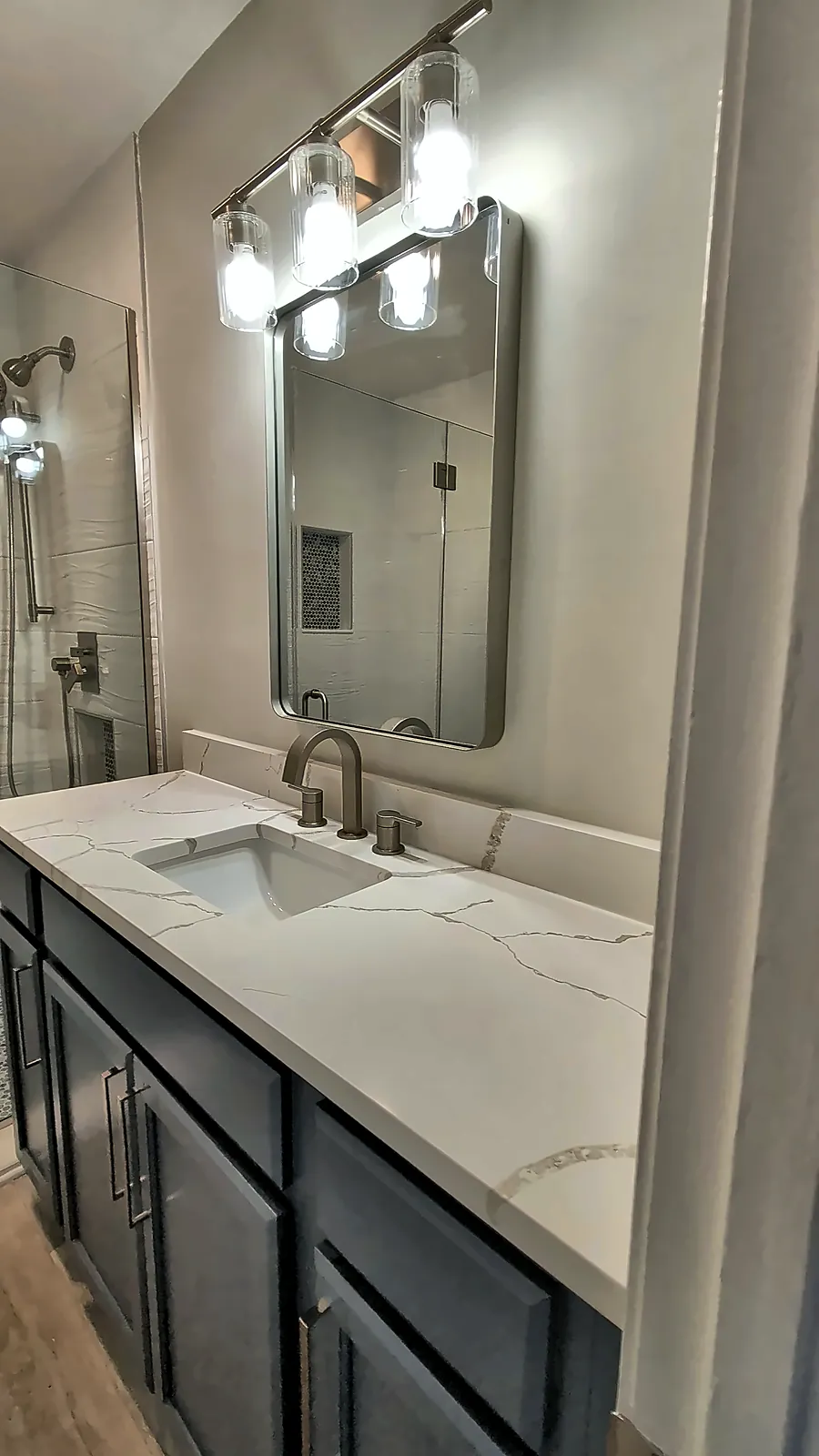 Navy bathroom vanity with quartz top and modern light bar