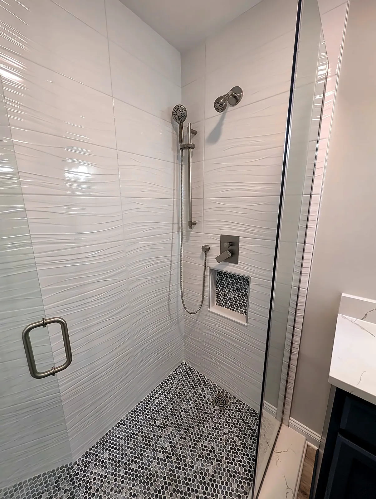 Tiled shower with handheld sprayer and pebble floor