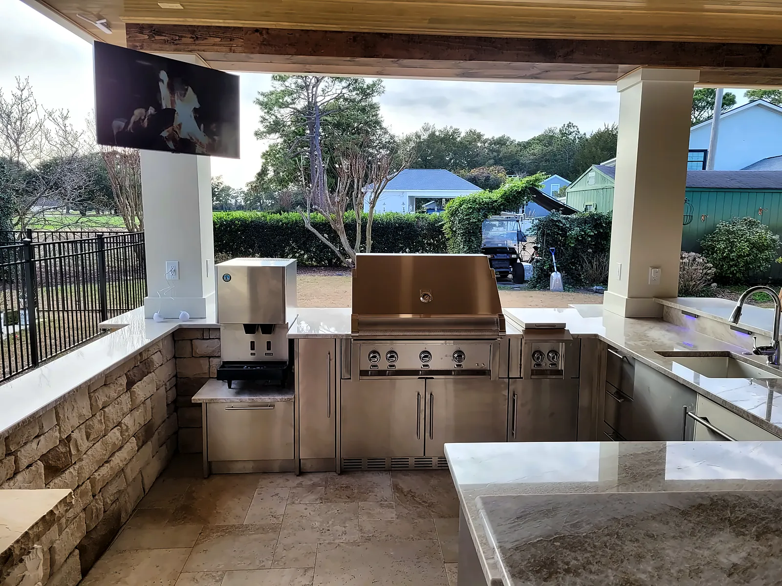 Outdoor kitchen with built-in grill, stone counters and pool views