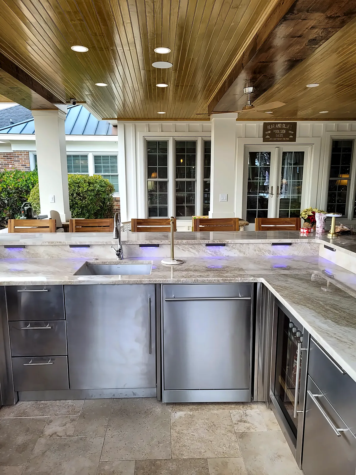L-shaped outdoor bar with stainless cabinetry and stone countertop