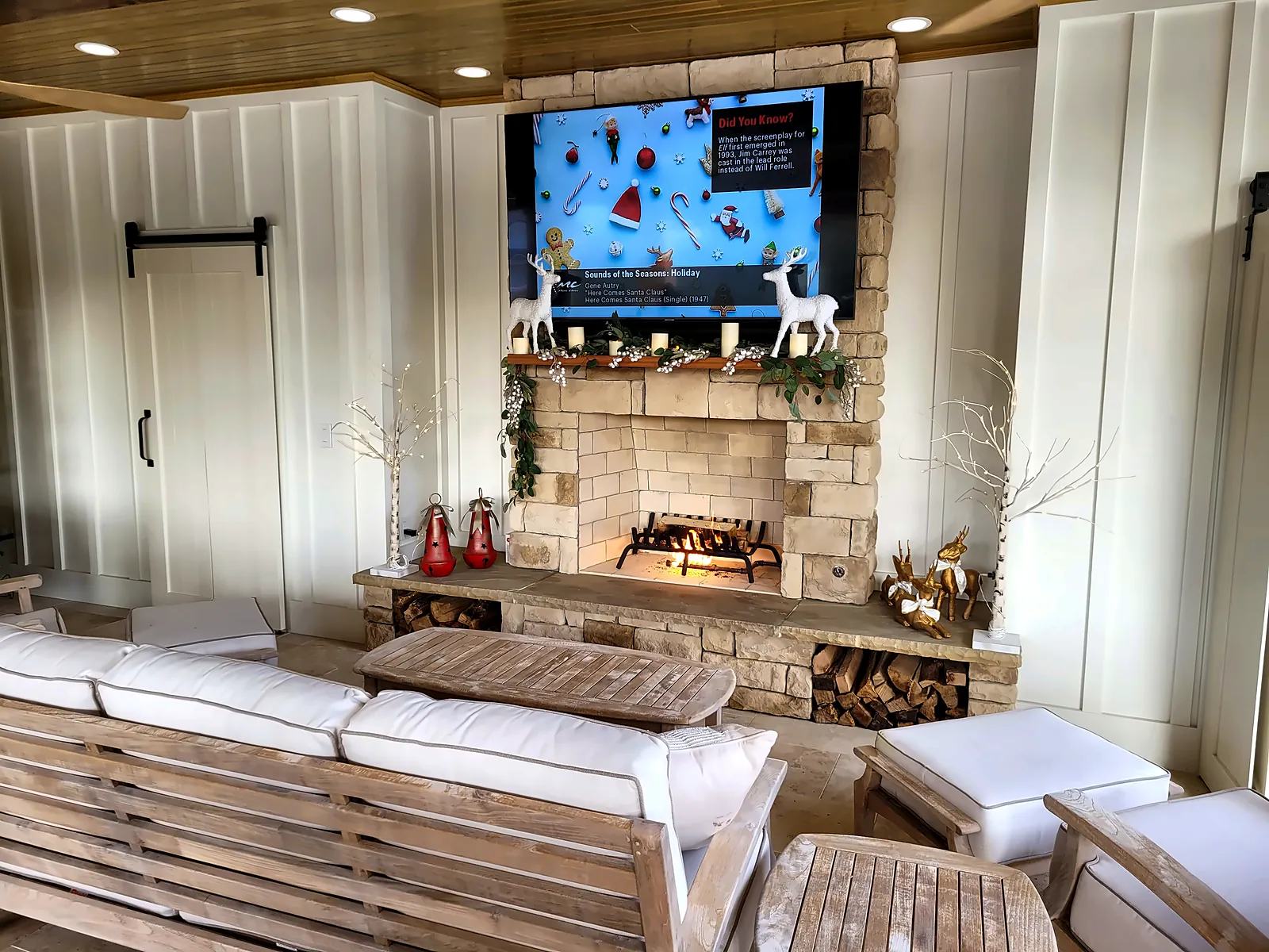 Outdoor fireplace wall with TV and lounge seating inside pavilion