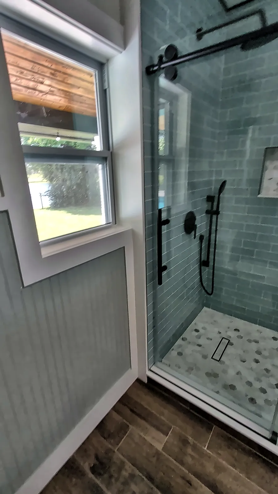Glass shower door with black hardware and subway tile