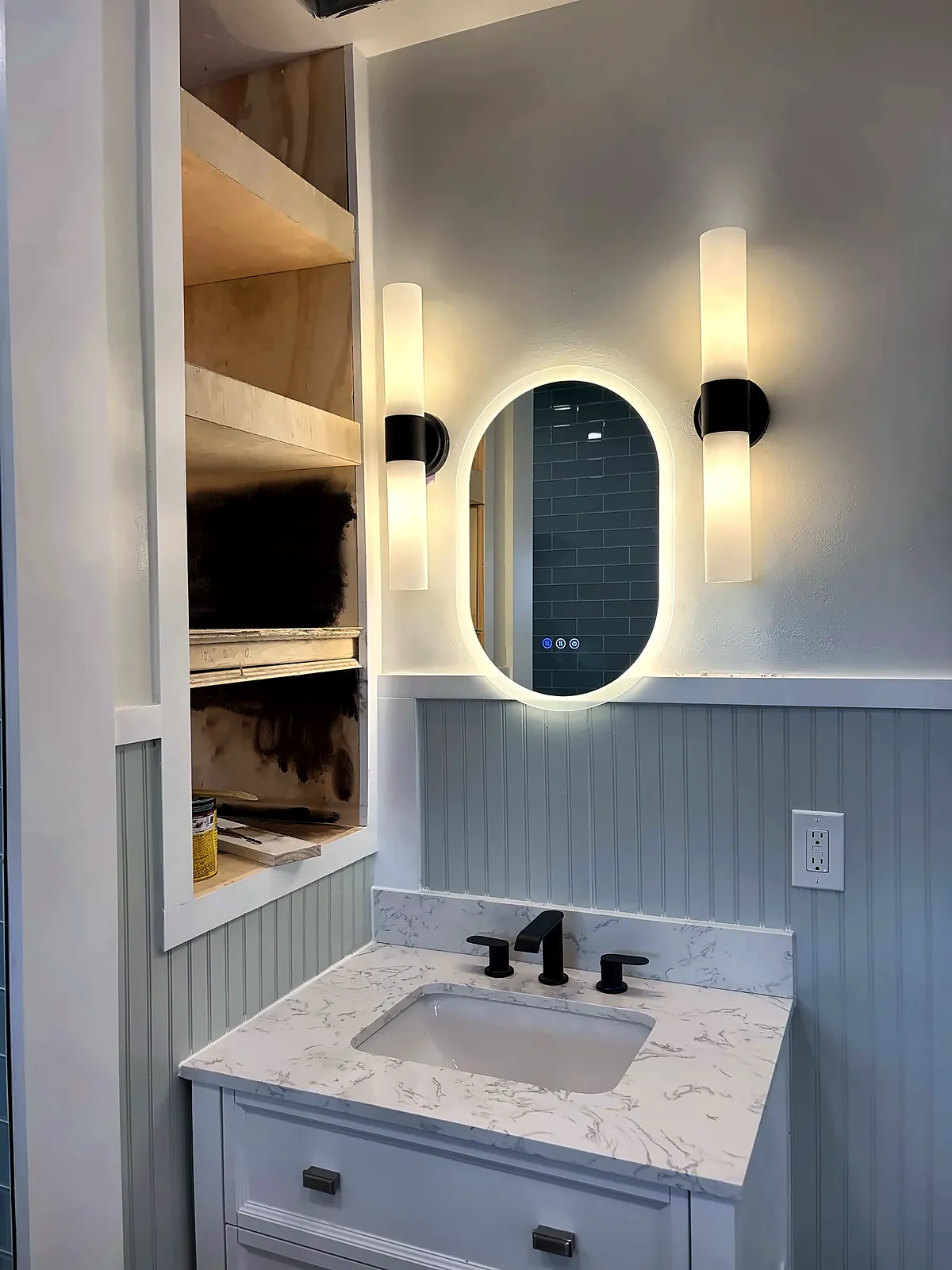 Vanity with backlit mirror beside open shelving