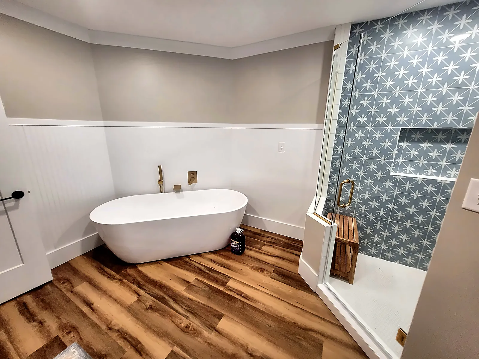 Primary bathroom with freestanding tub, wood-look floor and patterned tile shower