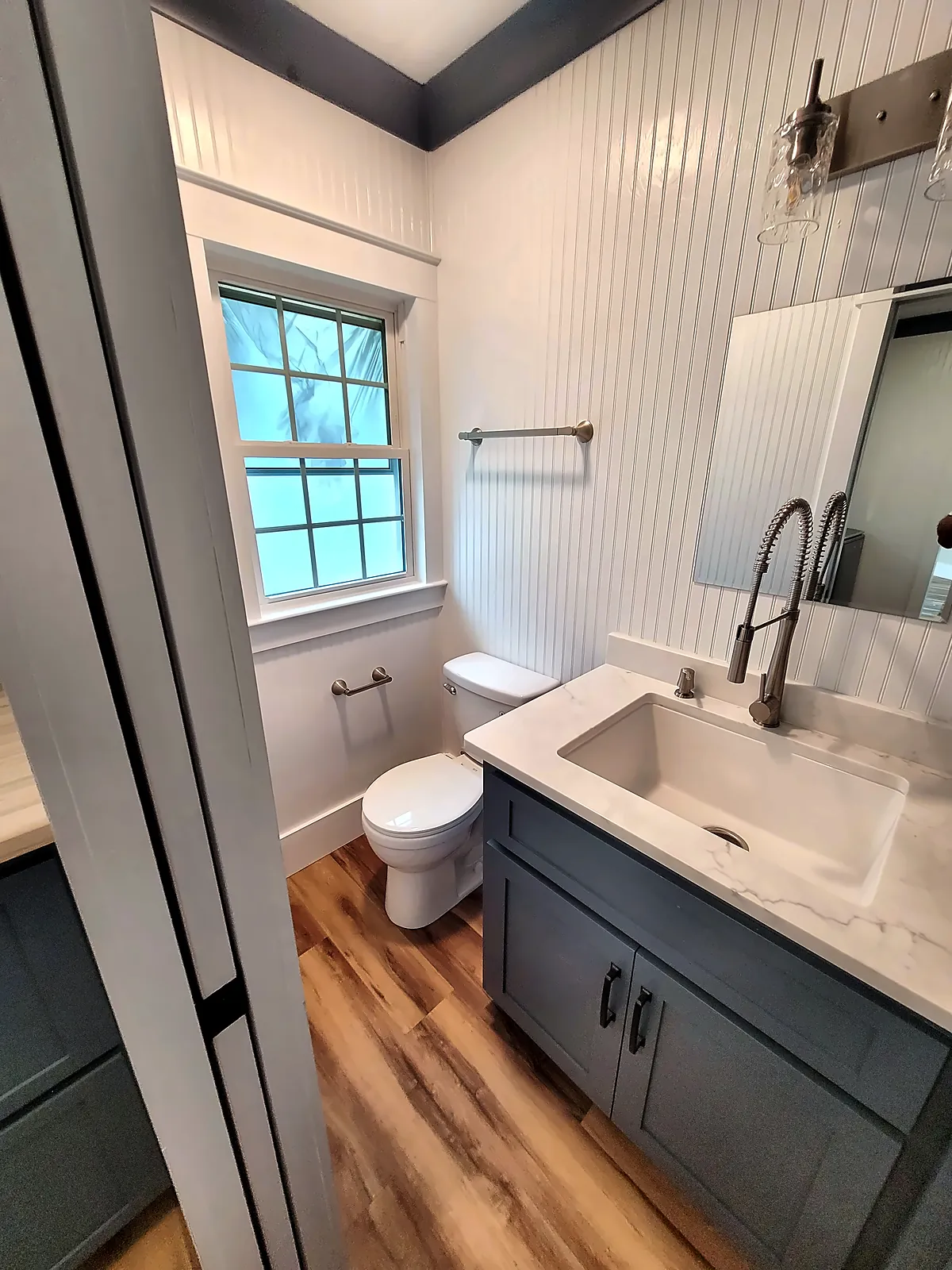 Bathroom with dark vanity, farmhouse sink and beadboard walls