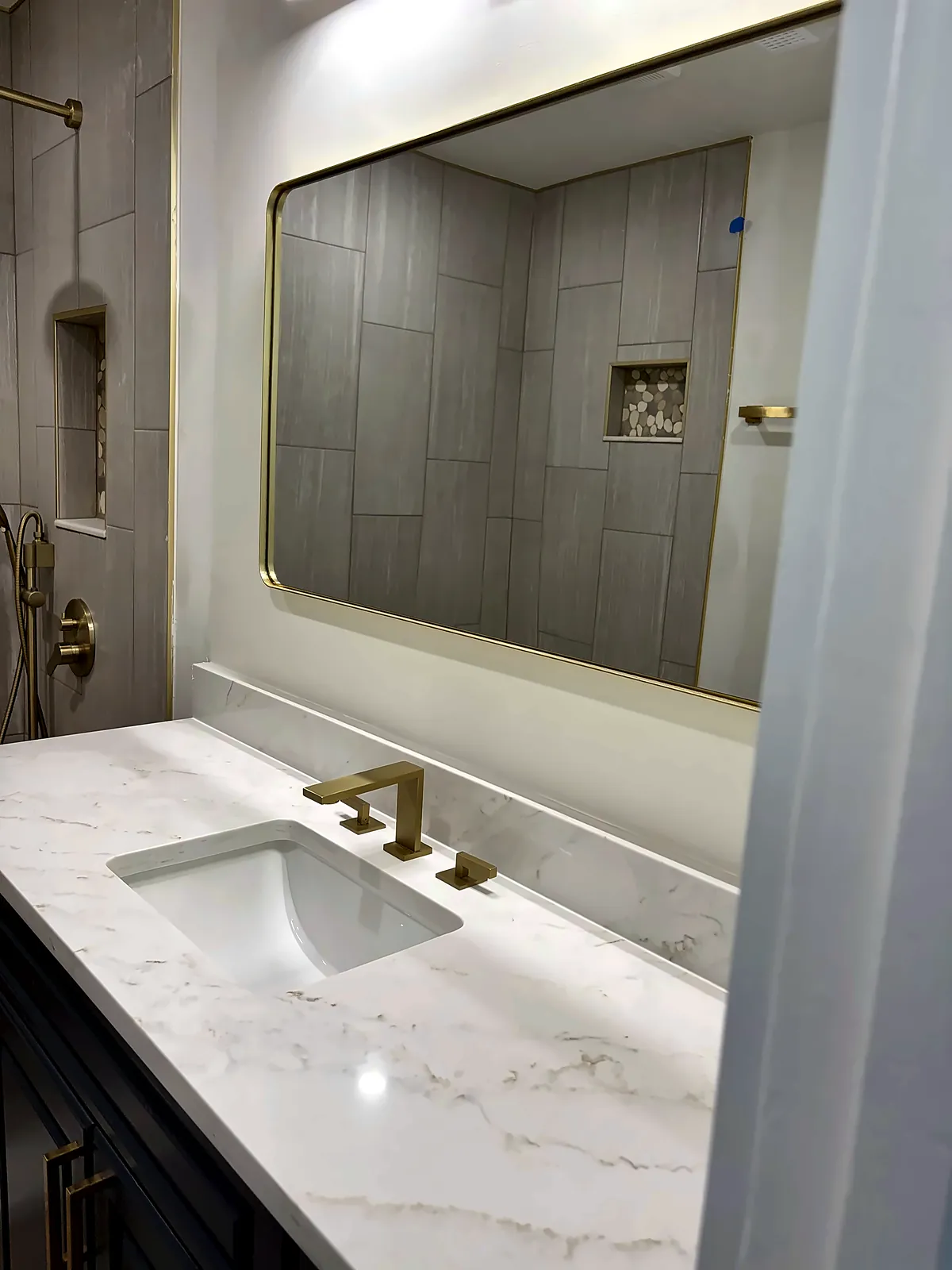 Quartz vanity with brushed-gold faucet and gold-framed mirror