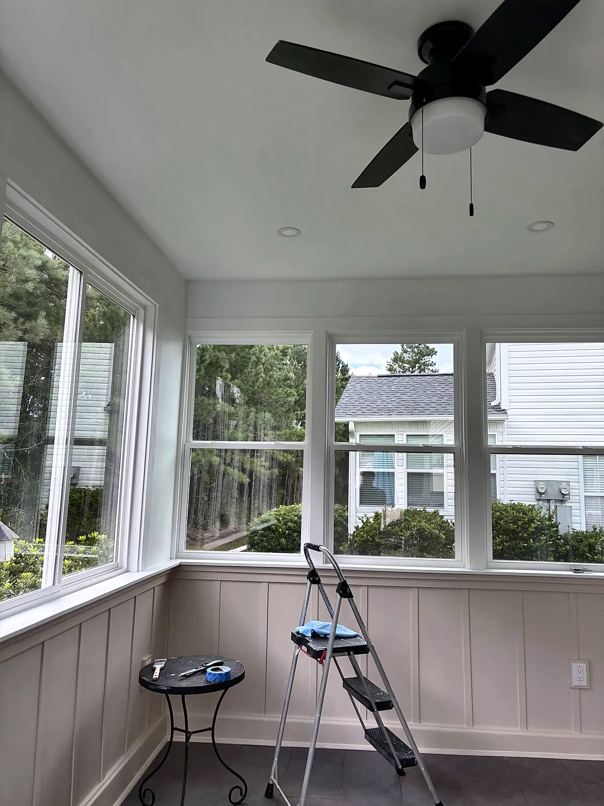 Bright four-season sunroom with ceiling fan and wainscot